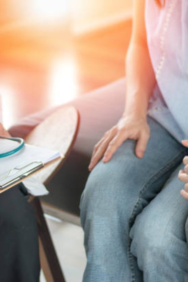 Infertility problem with marriage couple concept. A fertility doctor or reproductive endocrinologist with man and women holding hand together in therapy consult session of inability to pregnant.