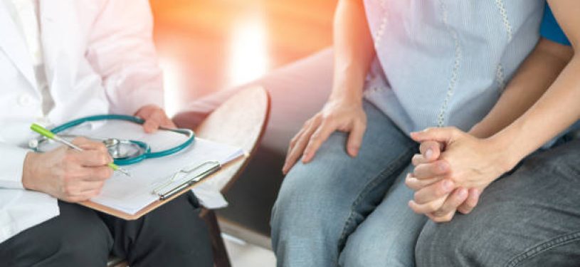 Infertility problem with marriage couple concept. A fertility doctor or reproductive endocrinologist with man and women holding hand together in therapy consult session of inability to pregnant.