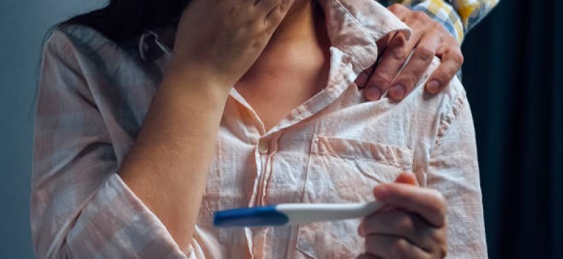 woman with pregnancy test. The man stays behind tense wife.